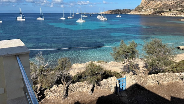 A coastal view with clear blue waters, boats, and rocky terrain. - Queen Deluxe Studio (Favignana)