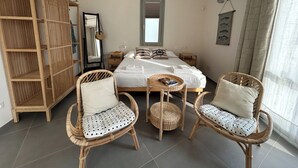 A bedroom with a bed, two wicker chairs, a wooden wardrobe, a mirror, and a ceiling fan. - Double Suite Apartment (Trapani)