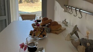 A table with pastries, a glass of coffee, and a decorative shell sculpture. - Double Suite Apartment (Trapani)