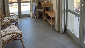 A room with a wooden desk, a chair, a television mounted on the wall, and a view of the sea through large glass doors. - Double Suite Apartment (Trapani)