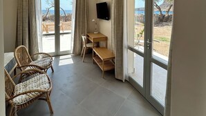 A room with a desk, two wicker chairs, a flat-screen TV, and large sliding glass doors offering a view of the outdoors. - Double Suite Apartment (Trapani)