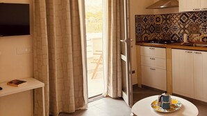 Une cuisine de taille réduite, dotée d’un ventilateur de plafond, d’un pare-feu en carrelage et d’une petite table à manger.