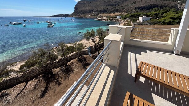 Un balcon offrant une vue sur une zone côtière, avec des bateaux sur l’eau et une montagne en arrière-plan.