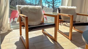 A wooden chair with white cushions in a room with large windows.
