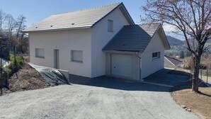 A single-story house with a garage, a sloped roof, and a gravel driveway.
