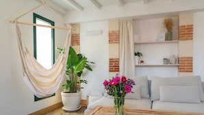 A living room with a hammock, a white sofa, a wooden coffee table, and a potted plant. - L'Arcachon | Hypercentre - Free Parking (Arcachon)