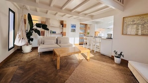A spacious living room with a wooden coffee table, a sofa, and a hanging plant. - L'Arcachon | Hypercentre - Free Parking (Arcachon)