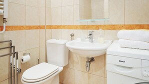 Ein Badezimmer mit Toilette, Waschbecken und einer Bosch Waschmaschine.