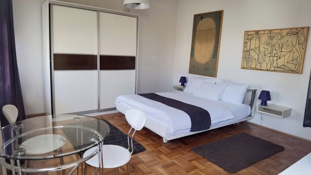 Ein modernes Schlafzimmer mit einem Bett, Nachttischen, einem Glastisch und einem Kleiderschrank.