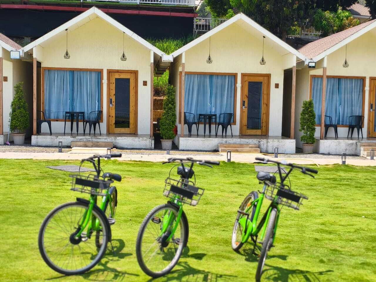 Una hilera de cabañas de una sola planta con un césped delantero, cada una con una bicicleta estacionada afuera.