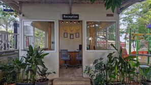 A reception area with a sign, two clocks, and a desk with chairs. - Blu Water Resort (Junnar)