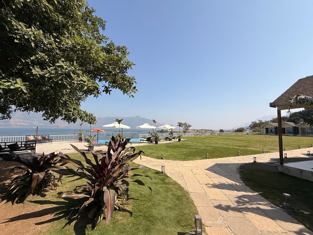 A patio area with a view of the sea, outdoor seating, and a covered structure.