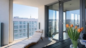 Ein Balkon mit Liegestuhl, Blumentopf und einer Vase mit Tulpen.