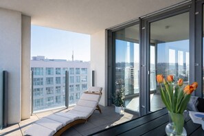 A balcony with a sun lounger, a potted plant, and a vase of tulips. - Elegant Karlín Apartment with Parking & Terrace by EasyBNB Premium (Prague)