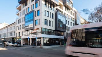 A multi-story building with a Starbucks Coffee on the ground floor, a tram in motion, and a pedestrian crossing.