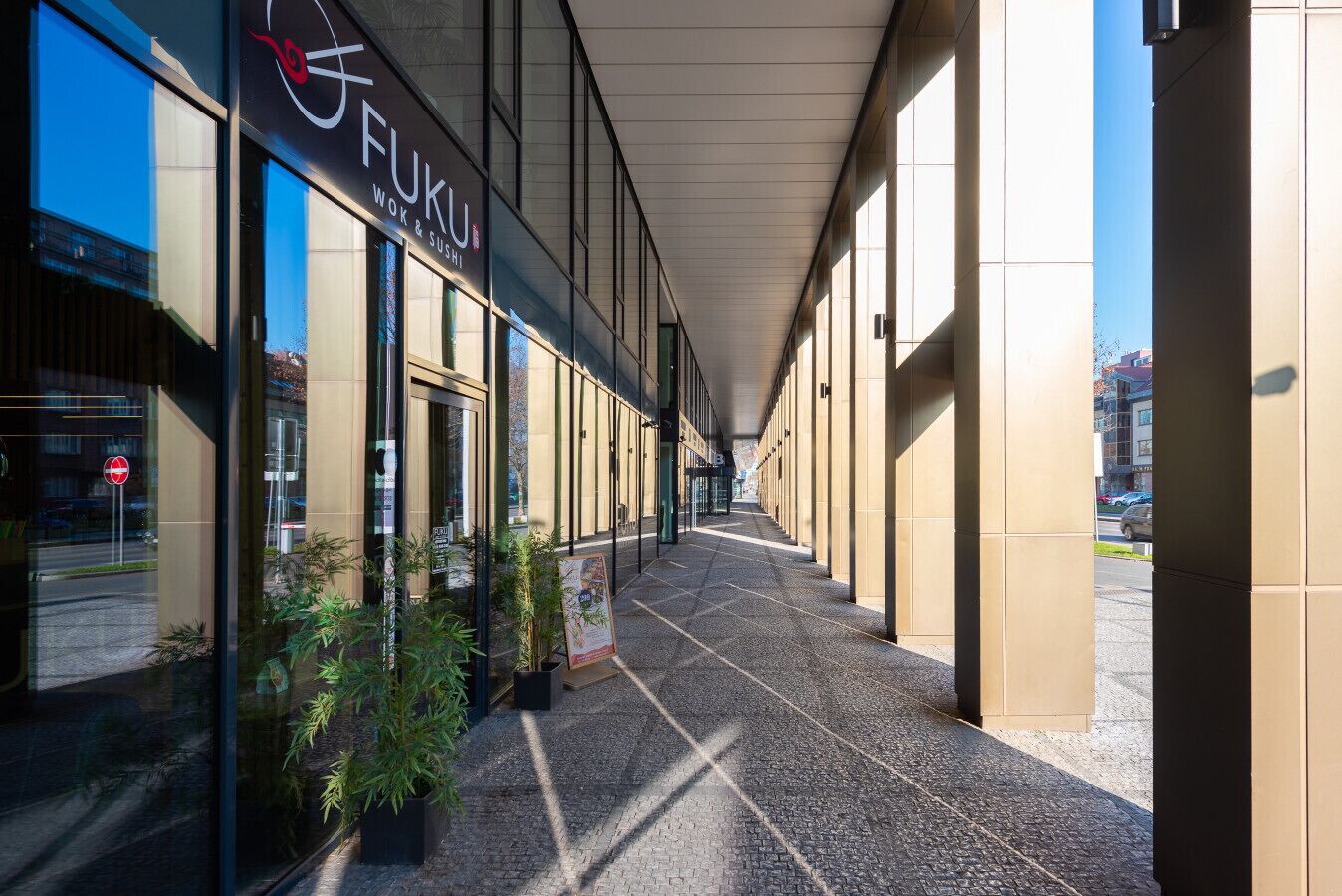 A covered walkway leading to a building with a sign reading "FUKU WOK & SUSHI".