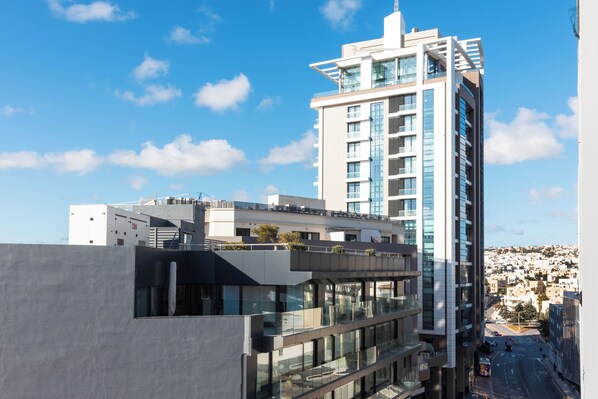 A modern high-rise building with multiple balconies and large windows, surrounded by other buildings and a clear sky. - Mercury Suites (St. Julian's)