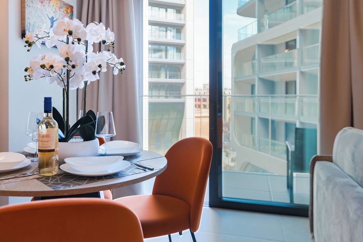 Un comedor con una mesa dispuesta para dos, una botella de vino y orquídeas blancas.