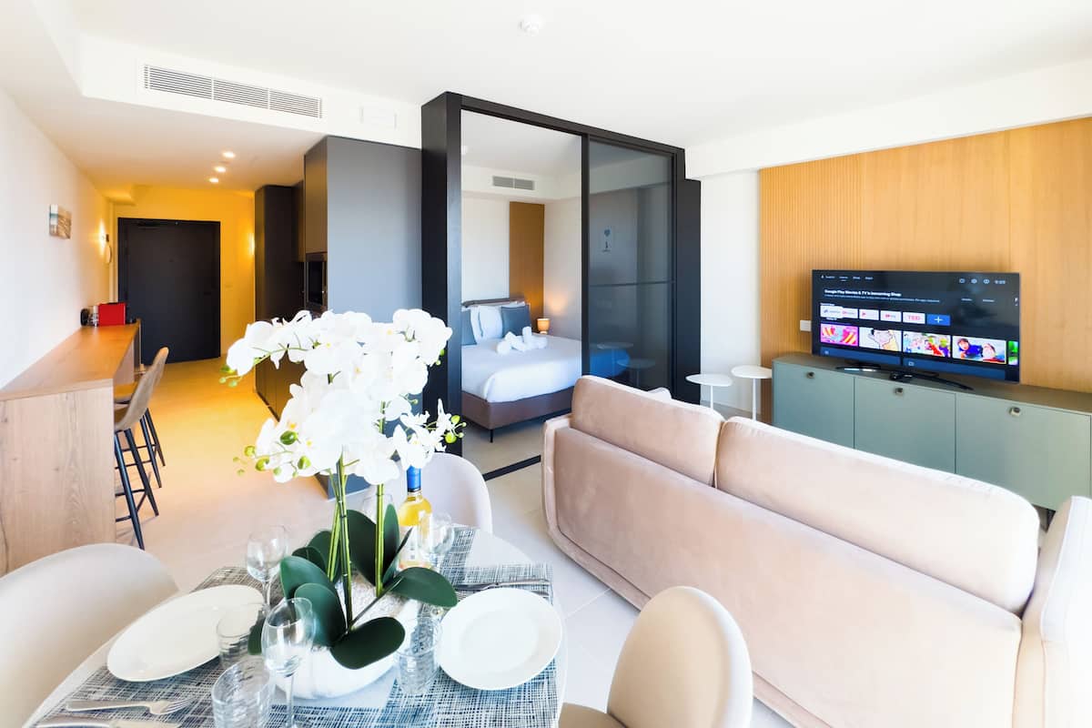 Una habitación de hotel moderna con comedor, sofá, televisor y cama.