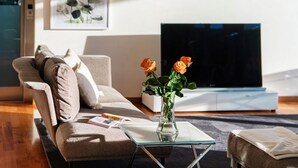 A modern living room with a sofa, a glass coffee table, a vase with flowers, and a flat-screen TV. - Villa Mara - MyHomeinComo (Como)