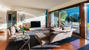 A modern living room with a sofa, TV, and a glass table. - Villa Mara - MyHomeinComo (Como)