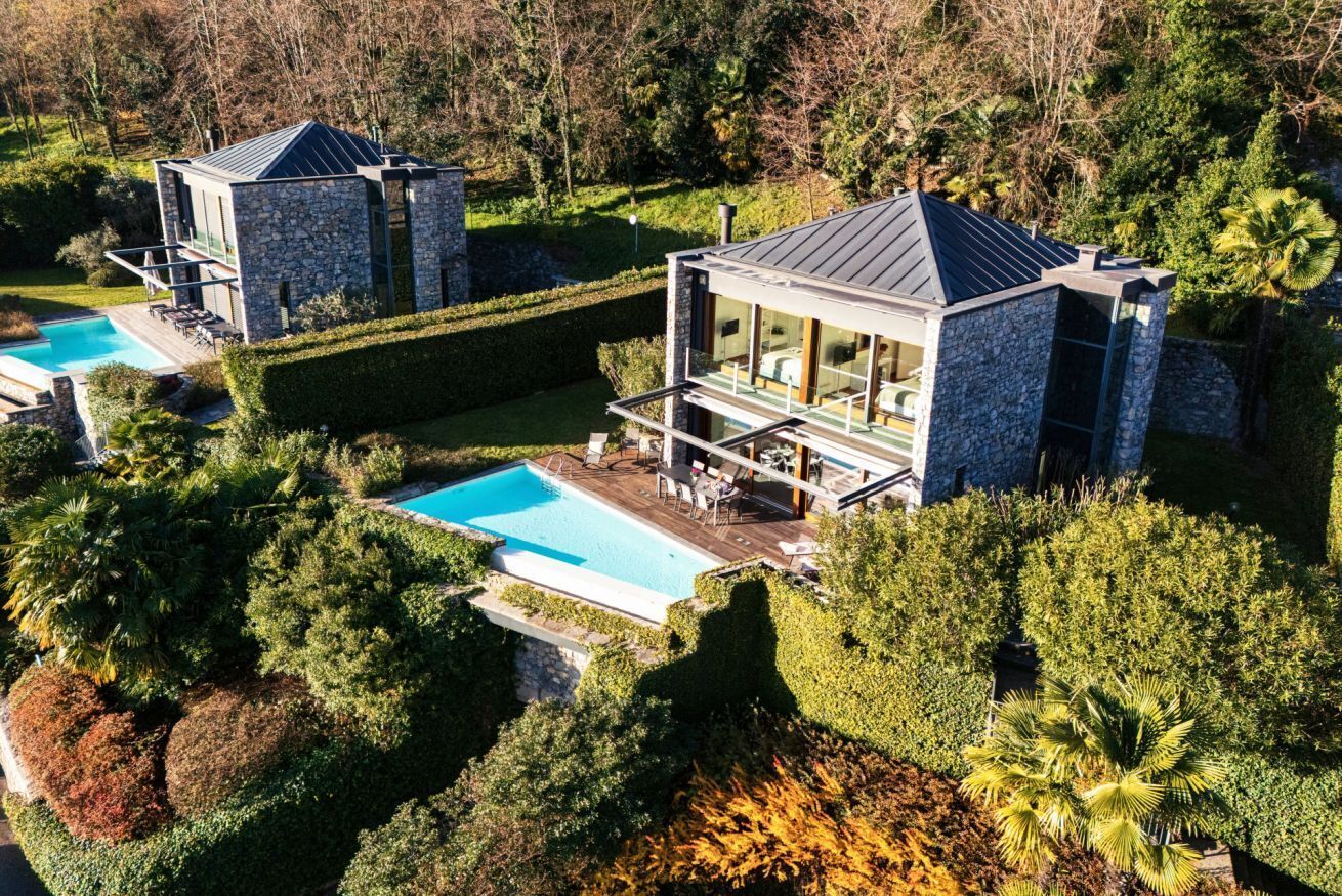 A modern house with a swimming pool, stone exterior, and a well-maintained garden.