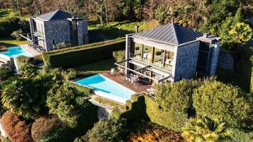 A modern house with a swimming pool, stone exterior, and a well-maintained garden.