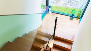 A wooden staircase with glass railings, leading to a room with a view of greenery outside. - Villa Mara - MyHomeinComo (Como)