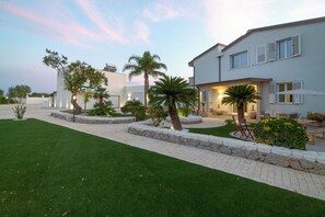 A modern house with a well-maintained lawn, stone pathways, and outdoor seating. - Exclusive detached villa with a heated outdoor pool and spa (Sicilia)