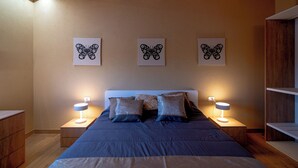 Ein Schlafzimmer mit einem Bett, zwei Nachttischen und drei Wandbildern mit Schmetterlingsmotiven.