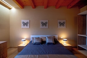 Ein Schlafzimmer mit einem Bett, zwei Nachttischen und drei Wandbildern mit Schmetterlingsmotiven.