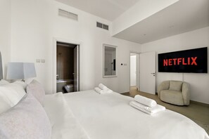 A hotel room with a large bed, a TV mounted on the wall, and a door leading to a bathroom. - Marina Arcade - 702 2BD (Dubai)