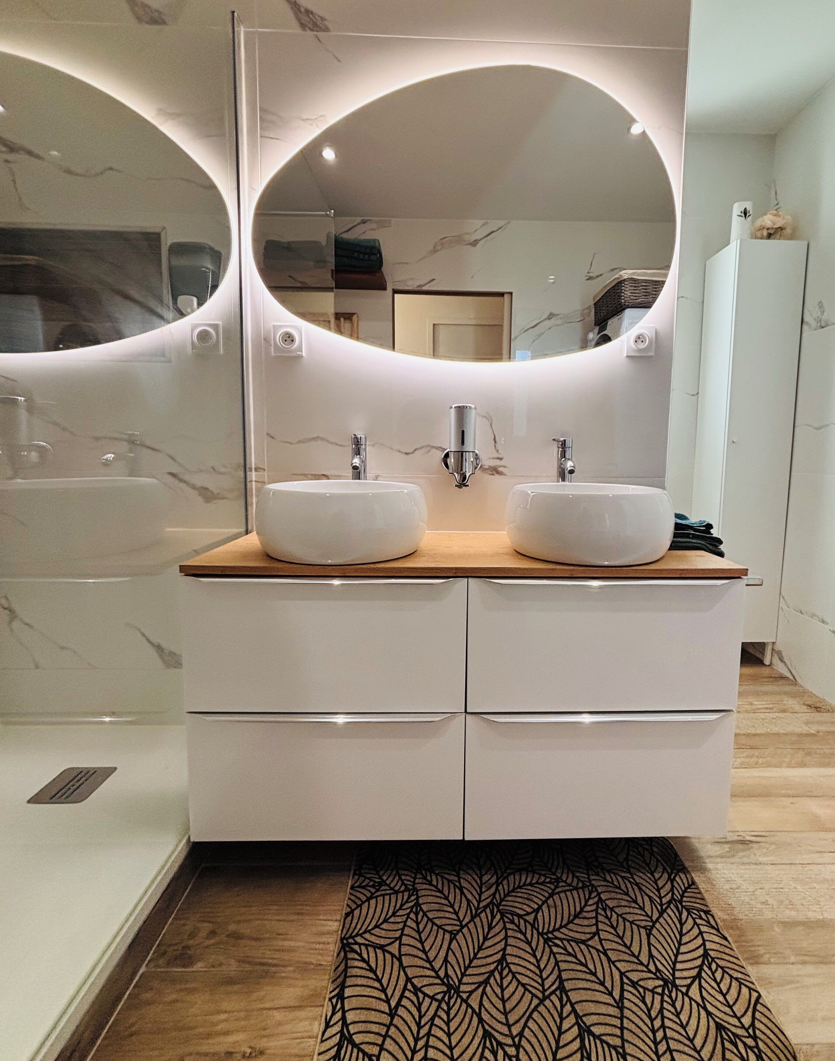 A modern bathroom with two sinks, a large mirror, and a wooden vanity.