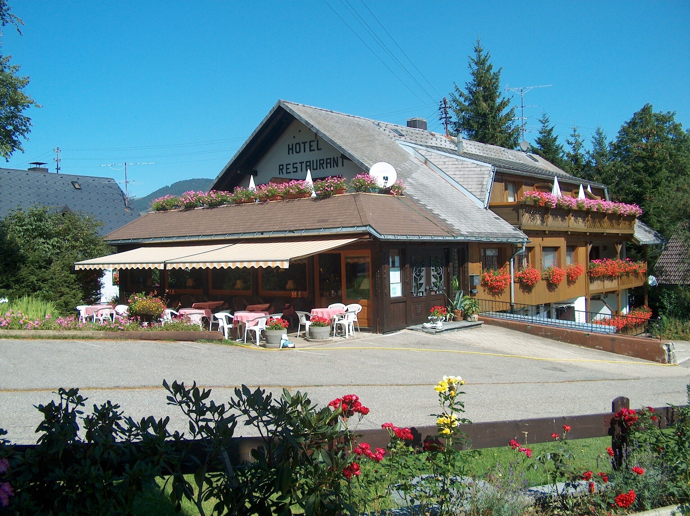 Un hôtel doté d’un restaurant, de tables en plein air et de jardinières sur le toit.