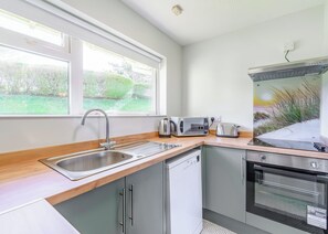 A modern kitchen with a sink, a toaster, a kettle, and a microwave. - Surf Wave Apartment 2 (Pets Welcome) (Woolacombe)