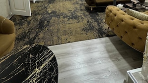 A spacious living area with a sectional sofa, a coffee table, and a patterned rug. - Sumaya Hotel (Tashkent)