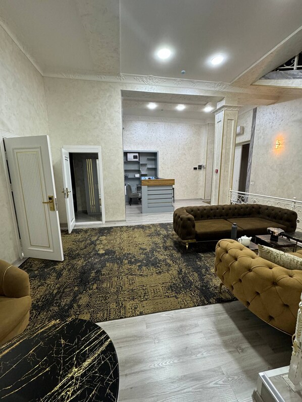 A spacious living area with a sectional sofa, a coffee table, and a patterned rug. - Sumaya Hotel (Tashkent)