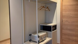 Un dressing accessible sans porte, doté d’étagères ouvertes, d’une tringle à vêtements et d’un petit meuble de rangement.