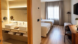 Une chambre d’hôtel avec salle de bain, un lit, un bureau et une télévision.