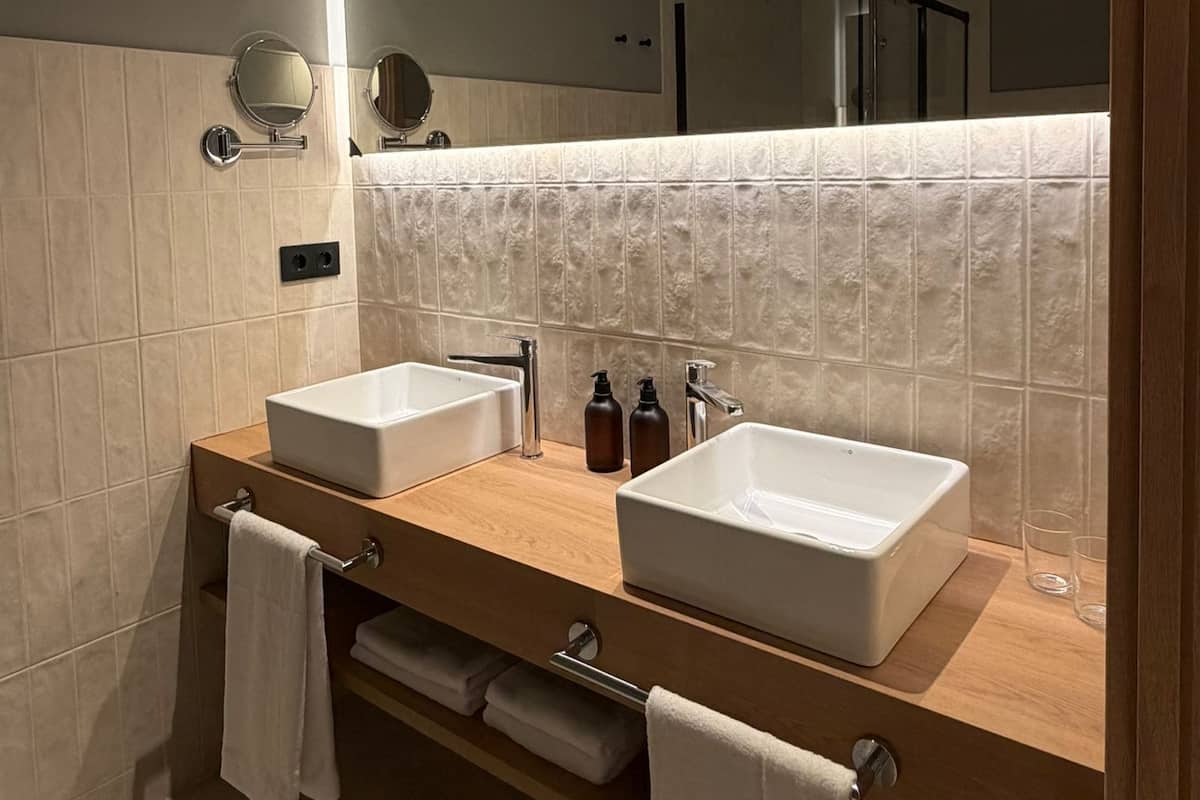 Une salle de bain moderne avec deux lavabos, un grand miroir et un porte-serviettes.