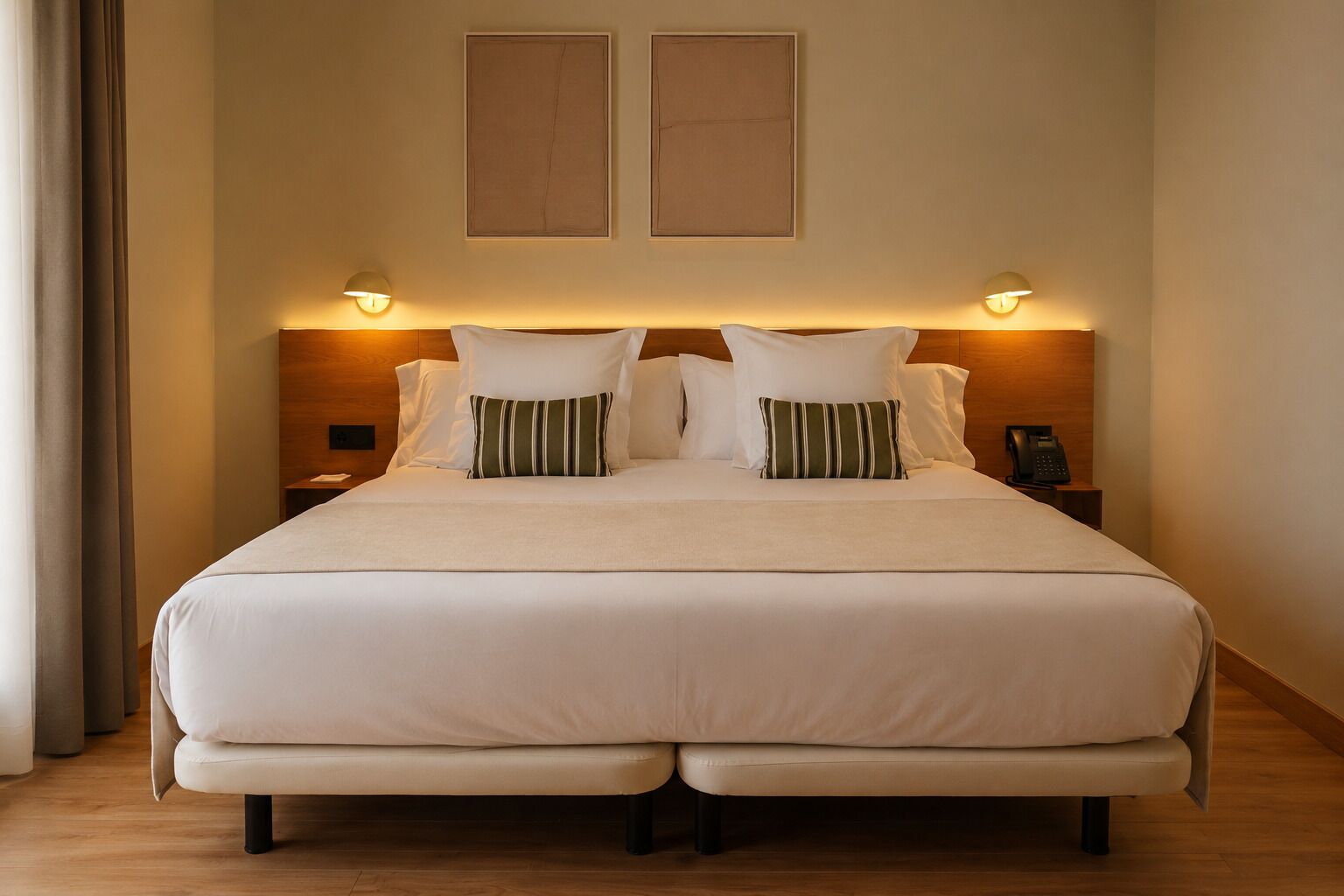 Una cama grande con cabecera de madera, dos mesitas de noche y un teléfono sobre una de ellas.