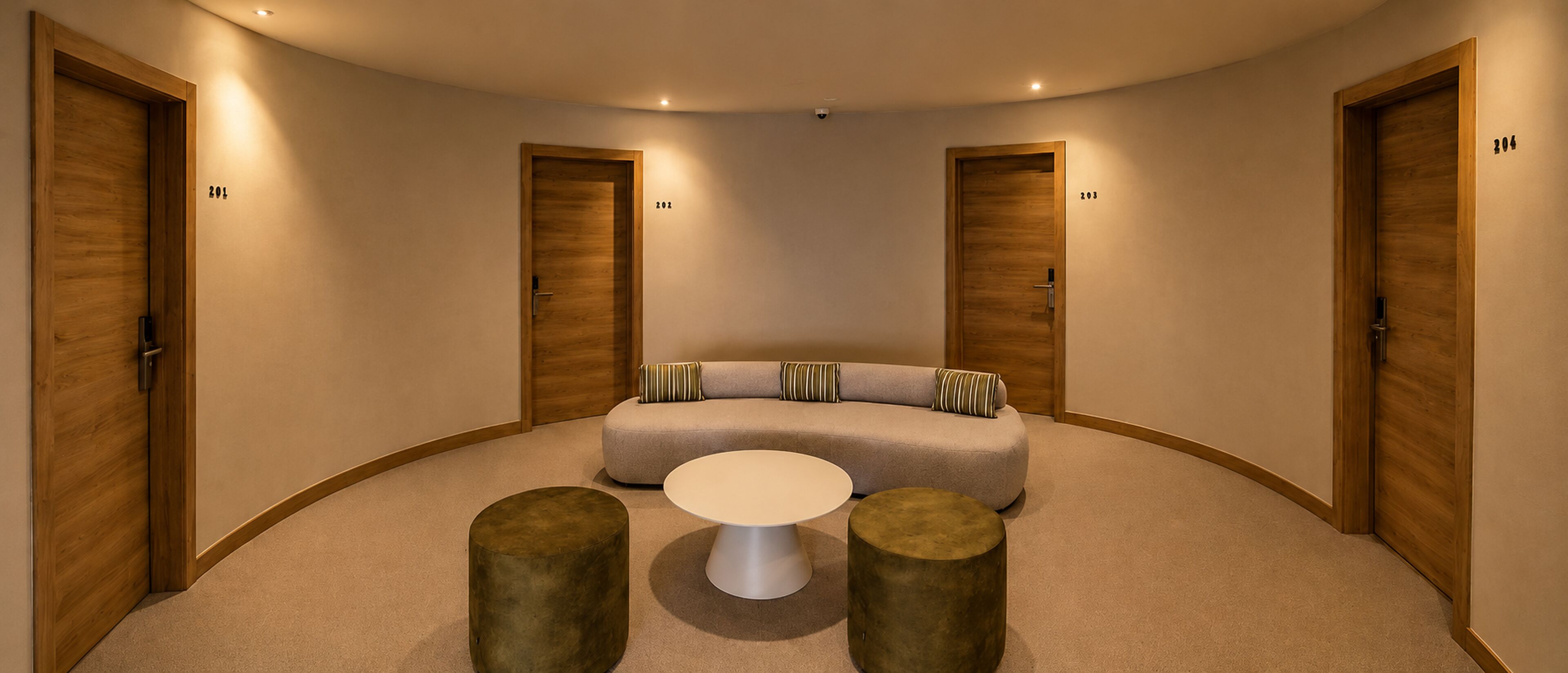 A circular room with a sofa, two stools, and a small table. There are two doors with numbers on them.