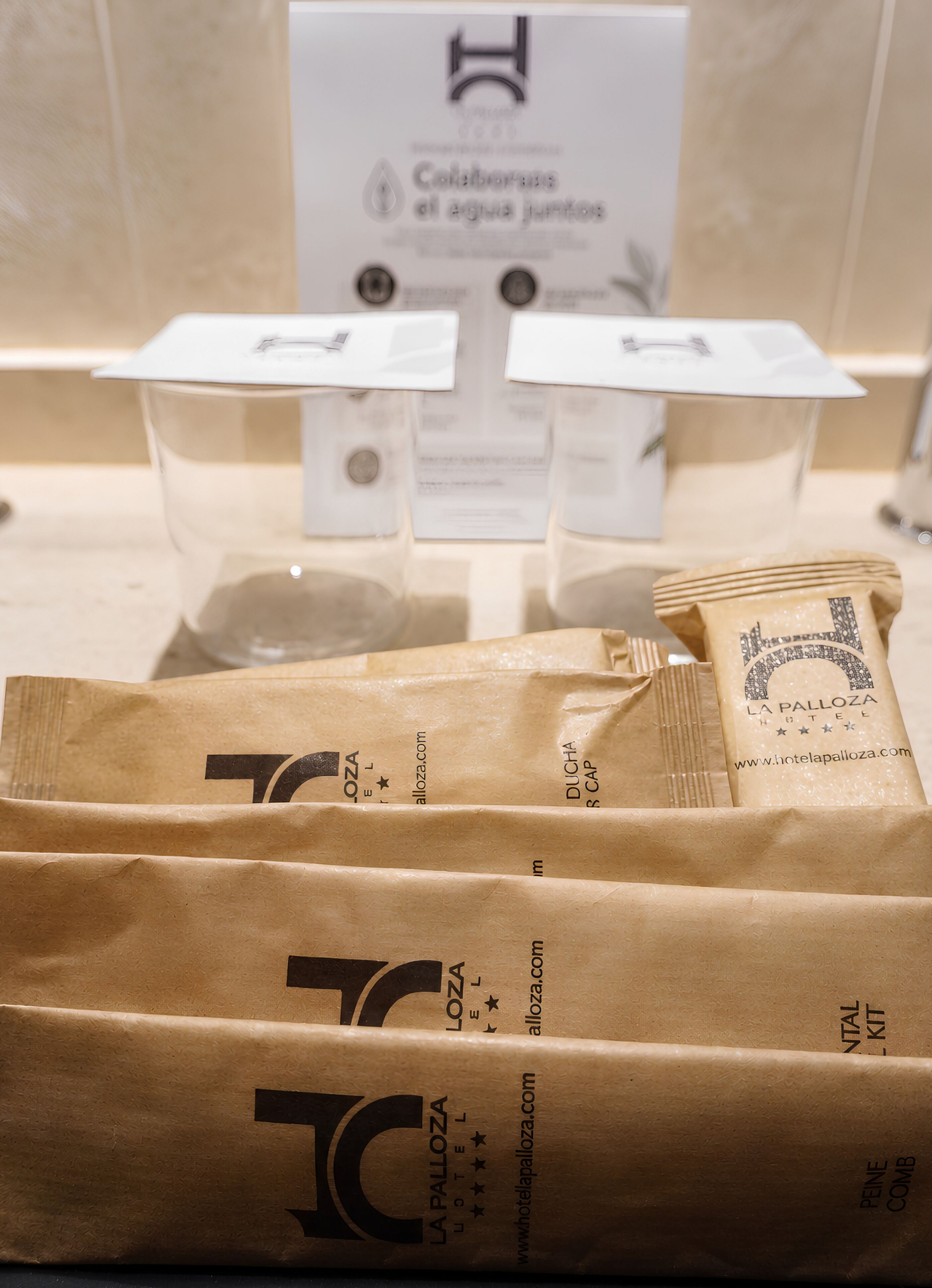 Exhibición de productos de La Palloza Hotel, entre ellos, bolsas de café y un cartel con el logotipo y sitio web del hotel.