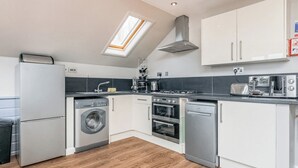 Een kleine keuken met een wasmachine, oven, vaatwasser en dakraam.