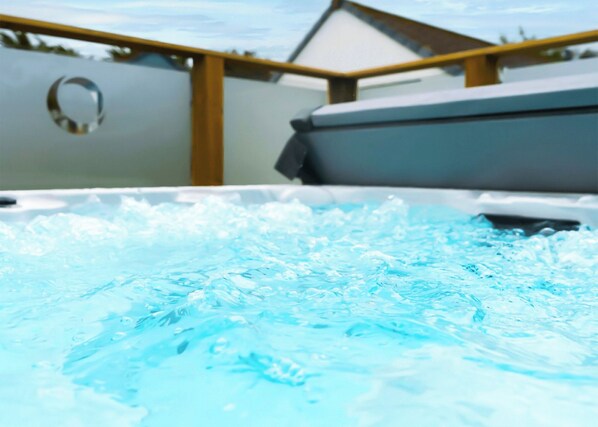 A hot tub with a wooden railing and a white wall in the background. - Ocean Breeze Villa 3 Hot Tub (Woolacombe)
