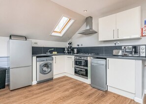A compact kitchen with a washing machine, oven, dishwasher, and a skylight. - Ocean Breeze Villa 3 Hot Tub (Pets Welcome) (Woolacombe)