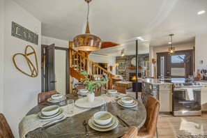 A dining area with a wooden table set for four, a staircase, and a kitchen with a modern stove. - Lakefront Pagosa Springs condo with mountain views, a private deck, grill, and remodeled interiors; three bedrooms and 2.5 baths sleep up to 5 guests. (Pagosa Springs, CO)