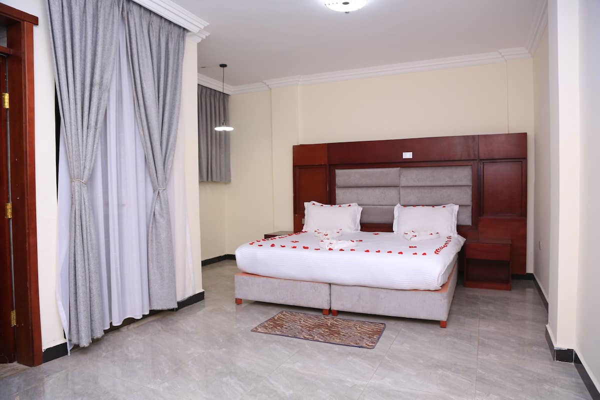 A bedroom with a large bed, a wooden headboard, and a small bedside table.