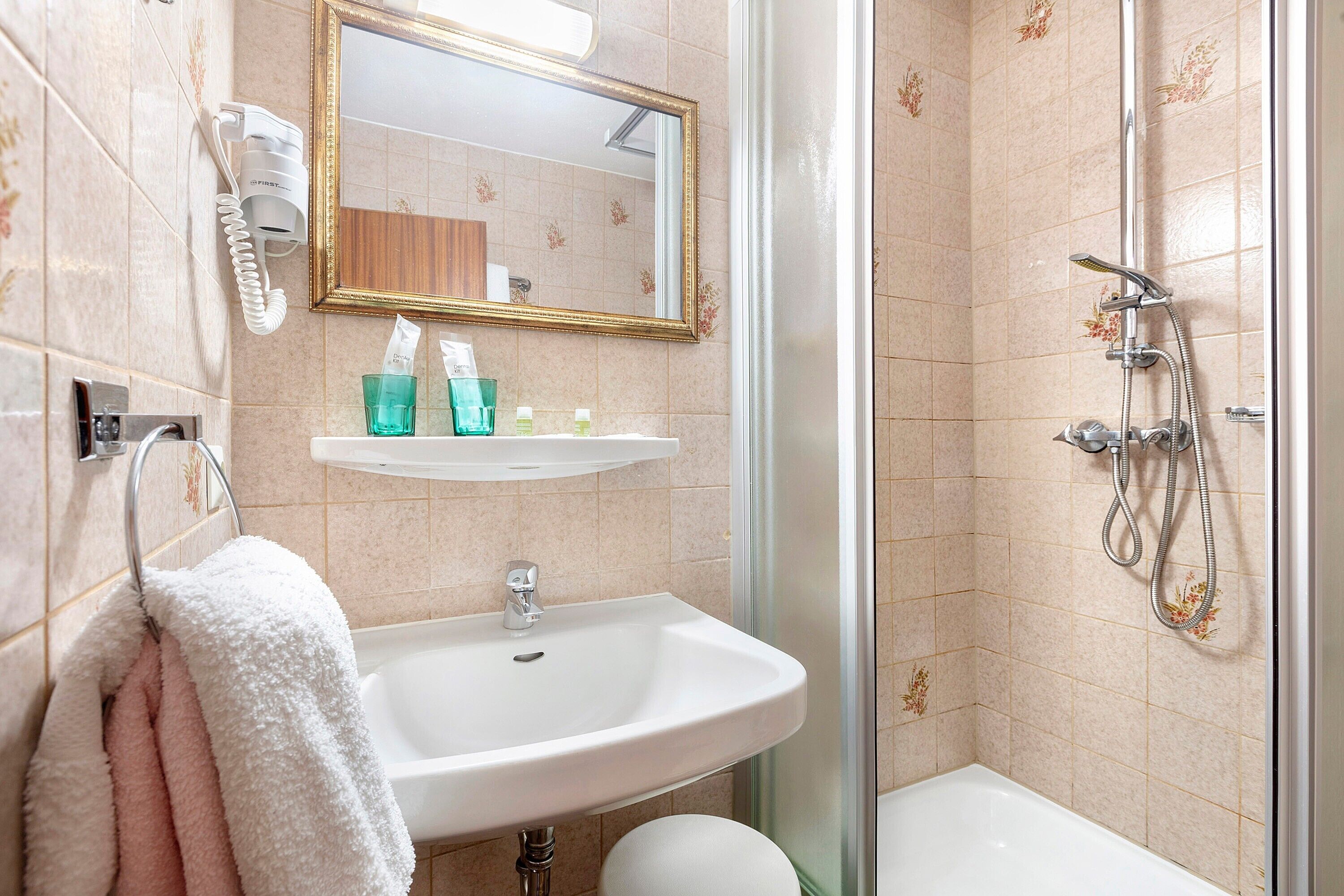 Une salle de bain équipée d’un lavabo, d’un miroir, d’un porte-serviettes et d’une douche.