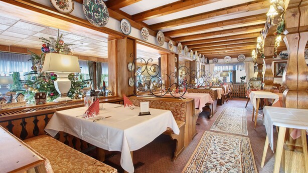A restaurant with wooden beams, white tablecloths, and patterned rugs. - Hotel Bären - Three-Star Double Room 7 / incl. Breakfast / 3 Guests / Balcony with Mountain View (Bernau im Schwarzwald)